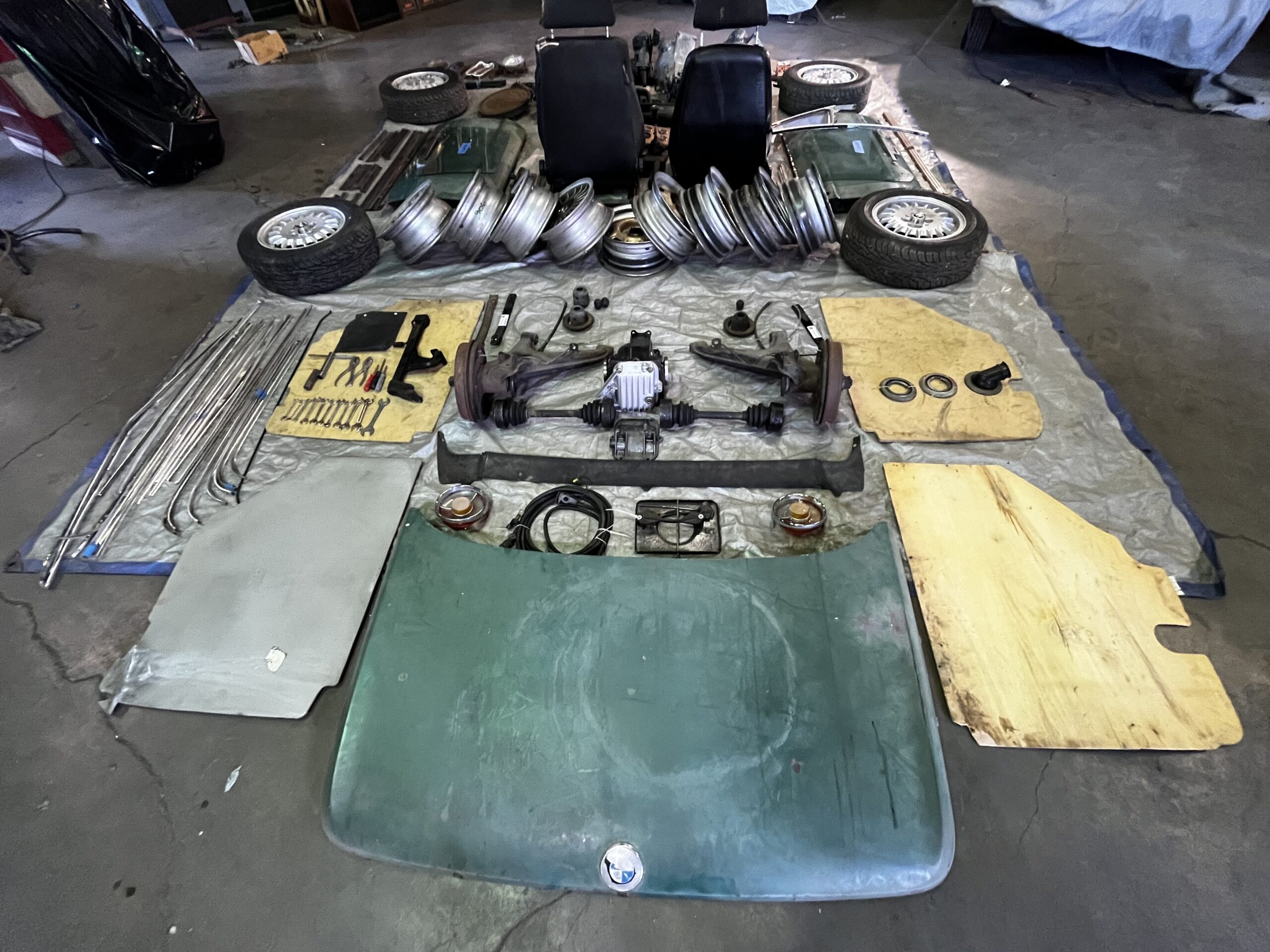 Dismantled BMW parts laid out: seats, wheels, trim and glass